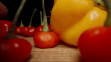 Ben yavaşça Sarı Habanero biberlerini ve Habanero Yıldızı çeşitliliğinin kırmızı biberlerini toplarken kamera masada geriye doğru hareket ediyor. Makro