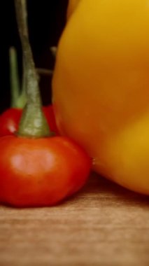 Dikey video. Ben yavaşça Sarı Habanero biberlerini ve Habanero Yıldızı çeşitliliğinin kırmızı biberlerini toplarken kamera masada geriye doğru hareket ediyor. Makro