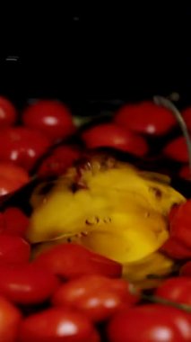 Dikey video. Siyah arka planda, Türkiye Yıldızı 'nın kırmızı biberleri suda yüzüyor ve sarı bir Habanero biberi yavaşça yere düşüyor..