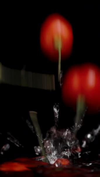 バーティカルビデオ トルコの星の赤いミニペッパーは 遅い動きで 黒い背景に水が飛び散って水に落ちる — ストック動画