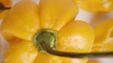Sarı Habanero biberinin düşüşünün ve dönüşünün yukarıdan aşağı görüntüsü, diğer biberler aşağıda yatarken. Hareket etki etmesi için yavaşlatıldı. Kapat.