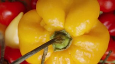 Aralarında Habanero, The Star of Turkey ve biberiyeli mini biberlerin de yer aldığı renkli biberlerin yer aldığı bir tabak, beyaz arka planda üst perdeden dönüyor. Dolly kaydırıcı aşırı yakın çekim.