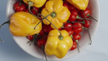 Baharatlı biber, Habanero ve The Star of Turkey biberlerinin karışımından oluşan bir tabağın yakın plan görüntüsü, beyaz arka planda en üstten dönüyor..