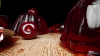 Kamera yüzeyde süzülüyor. Tahtadaki kırmızı kiraz jölesi arasında. Dolly kaydırıcı aşırı yakın çekim.