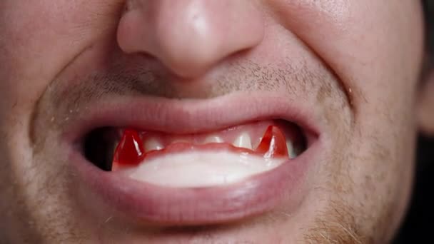 Genç Bir Adam Ağzında Vampir Dişi Şeklinde Şekerlemelerle Sırıtıyor Yakın — Stok video