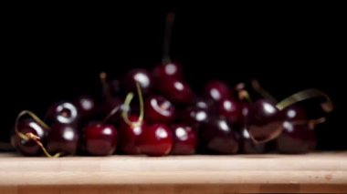 Ağır çekimde, bir kiraz tahtadan siyah arka plana düşer..