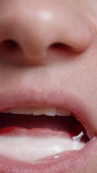 バーティカルビデオ 若い女性は彼女の口を開き ヴァンパイアの牙のように形をしたガミーキャンディーを明らかにし 遊んで彼らとやり取り クローズアップショット — ストック動画