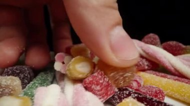 Şekerle tozlanmış çeşitli renk ve şekillerde bir avuç dolusu jelibon alıyorum. Dolly kaydırıcı aşırı yakın çekim.