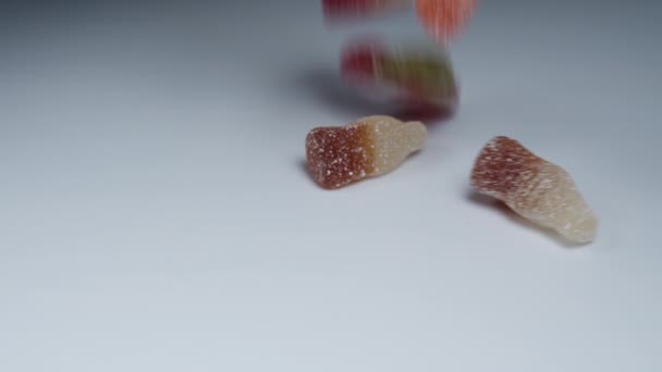 砂糖でほこり ホワイトテーブルに落ちるさまざまな風味のアソートされたガミーキャンディーのミックス — ストック動画