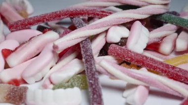 Şeker kaplı jelibon karışımından bir avuç alıyorum ve yavaşça masaya fırlatıyorum..