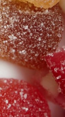 Dikey video. Farklı şekillerde ve tatlarda çeşitli renkli şekerlerin karışımı. Üst Manzara. Dolly kaydırıcı aşırı yakın çekim.