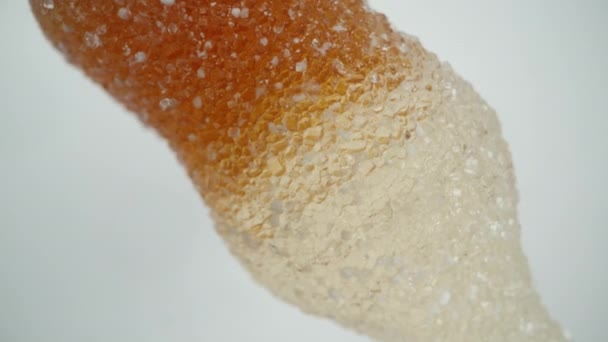 砂糖にコーラボトルの形をしたガミーキャンディーのシミュレーション落下 白い背景に回転 — ストック動画