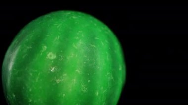 Yeşil karpuz şeklinde jelibon şekeri. Siyah arka planda düşme simülasyonu. Dolly makro yakınlaştırma.