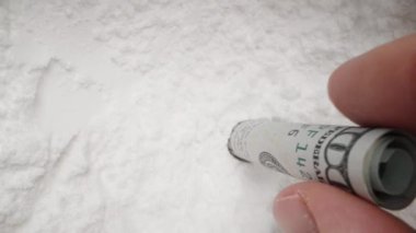 100 dolarlık banknotu yuvarlayarak beyaz tozu içine sokuyorum. Uyuşturucu kullanımı ve kokain kavramı. Dolly kaydırıcı aşırı yakın çekim.