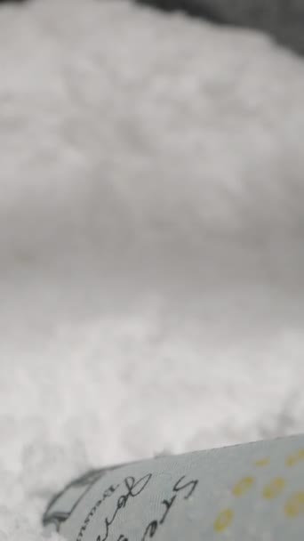 バーティカルビデオ コカインと薬物の使用の概念を描いた 白い粉の山に巻かれた100ドルの法案 ドリースライダー極端なクローズアップ — ストック動画