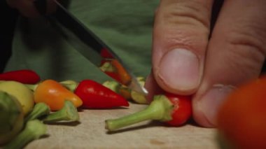 Kamera ahşap tahta boyunca geriye doğru süzülüyor, çok renkli kırmızı biberlerin filizlerini keserken yakından çekiyor..