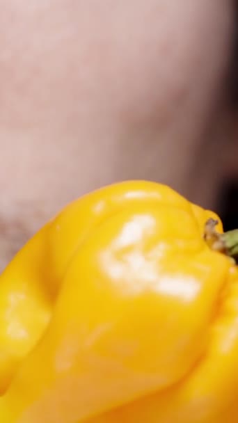 垂直录像 在特写镜头中 一个男人把舌头摸到一个辛辣的黄色哈巴内罗胡椒 他因为热而面带微笑 — 图库视频影像