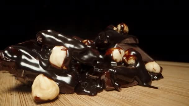 Broken Chocolate Squares Sprinkled Hazelnuts Drizzled Chocolate Rotate Wooden Board — Stock Video