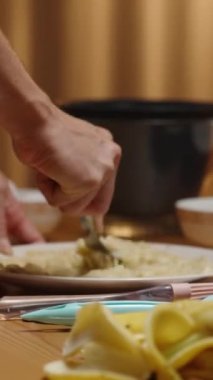 Dikey video. Genç bir kadın muz püresi yaparak tatlıyı hazırlıyor..