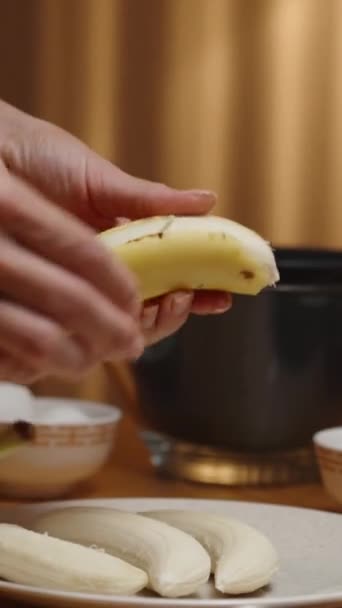 Вертикальное Видео Женщина Готовит Десерт Очищает Бананы Миски Ингредиентами Столе — стоковое видео