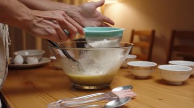 Bir kadın unu cam kaseye yavaş çekimde süzer. Pasta yapma sürecinin bir parçasıdır..