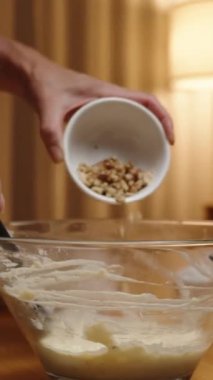 Dikey video. Pasta hamuruna ceviz ekliyorum. Sıcak bir lambanın parıltısında.