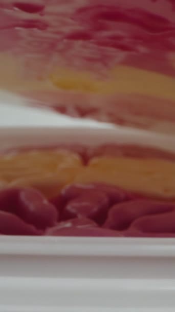 垂直录像 粉红色的冰淇淋装在一个大的白色容器里 我打开它 相机从上面滑行 多利滑翔机极端特写 — 图库视频影像