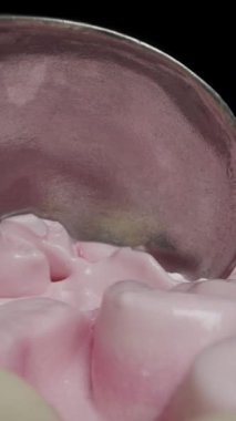 Dikey video. Özel bir metal kepçesiyle pembe dondurmayı topa çeviriyorum. Dolly kaydırıcı aşırı yakın çekim.