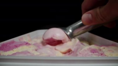 Özel bir kaşık kullanarak bir kepçe pembe dondurma yapıp waffle külahının içine koyuyorlar. Dolly kaydırıcı aşırı yakın çekim.