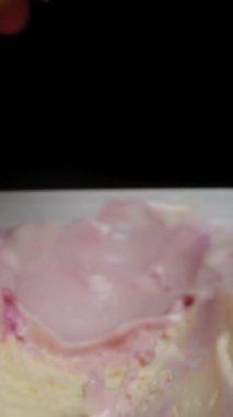 Dikey video. Pembe dondurma kepçesi waffle külahından diğer dondurmalarla birlikte kabın içine düşer ve kaşık onun yanına yerleştirilir..