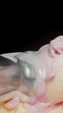 Dikey video. Dondurma toplarını kepçelemek için kullanılan metal dondurma kepçesi waffle külahıyla birlikte kutunun içinde. Kamera yaklaştıkça waffle külahını yakalıyorum..