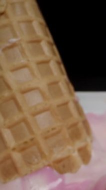 Dikey video. Özel kaşığı bir kepçe pembe dondurmayla waffle külahının yanına koyuyorum. Dolly kaydırıcı aşırı yakın çekim.