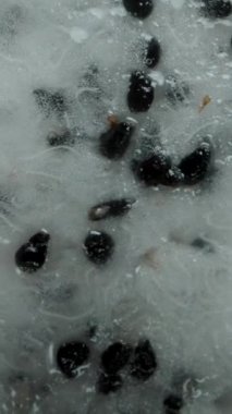 Dikey video. Beyaz tenli Pitaya ya da Ejderha Meyvesi 'nin yarısı siyah arka plan, düşen konsept ya da makro yakınlaştırma efekti üzerinde döner.