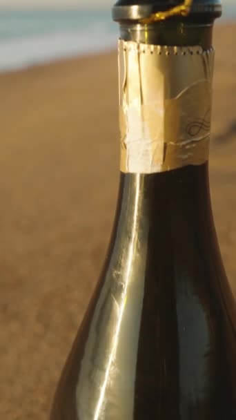 垂直录像 日出时在海滨的一个开着的香槟酒瓶 瓶颈上挂着一个红色的装饰品 一个圣诞装饰品 — 图库视频影像