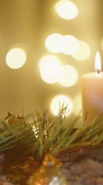 Dikey video. Noel süsleriyle süslenmiş çelenk ve mumların sıcacık parıltısıyla sıcacık bir Noel evi. Kaydırıcı