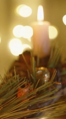 Dikey video. Kamera yavaş yavaş geriye doğru kayıyor. Dekorasyon ve mumlarla dolu samimi bir Noel evini gözler önüne seriyor..