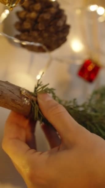 バーティカルビデオ 女性が新年の装飾を作り 熱い接着剤銃を使用して木の枝を接着しています — ストック動画
