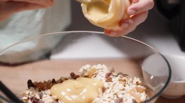 Bir kadın ev yapımı granola yapıyor. Tahıl ve fındıklara elma püresi ekliyor..