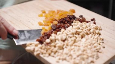 Kadın ev yapımı granola malzemelerini kesmiş ve ağır çekimde bir kaseye koyuyor..