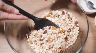 Granola, tahıl ve fındık ve meyve karışımı karışımları büyük bir kasede karıştırılıyor..