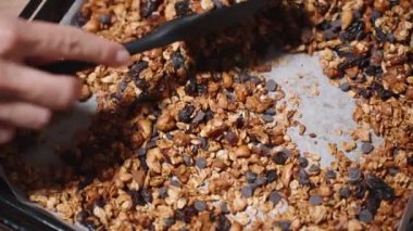 Fırından yeni çıkmış bir spatulayla taze pişmiş tahılları karıştırıyor. Yavaş çekim.