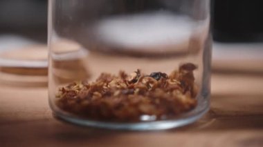 Yeni hazırlanmış ev yapımı tahılları bir kavanoza koyuyorlar, yavaş çekimde, tanecikler dağılıyor..