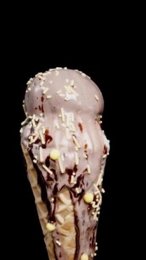 Dikey video. Erimiş dondurmalı waffle külahını alıp, siyah bir arka plana yaslıyorum..