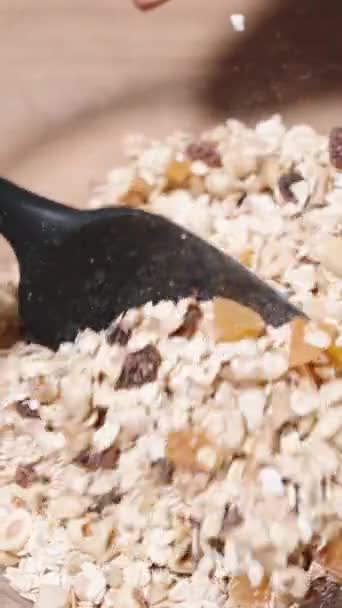 垂直录像 格拉诺拉的配料 谷物以及坚果和水果的混合物 被混合在一个大碗里 — 图库视频影像
