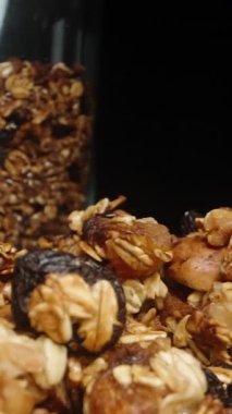 Dikey video. Plakadan bir kaşık tahıl aldım, siyah bir arka plana karşı. Yavaş çekim.