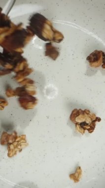 Dikey video. Tahıl gevreğinin bir tabağa dökülüşünün üst görüntüsü. Dolly kaydırıcı aşırı yakın çekim.