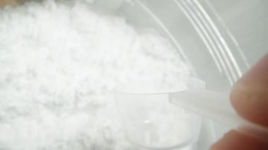 Yavaş çekim, pov makro video. Elimde bir kaşık tutarak, kavanozdan beyaz toz topluyorum ve bardağa döküyorum. Spor ek konsepti.