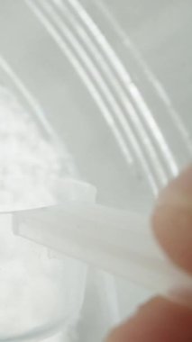 Dikey video. Yavaş çekim, pov makro video. Elimde bir kaşık tutarak, kavanozdan beyaz toz topluyorum ve bardağa döküyorum. Spor ek konsepti.