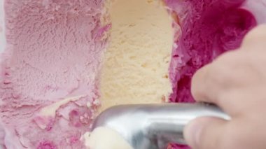Dikey video. Dondurmanın üç farklı çeşidi ve renginde pembe olanın arasında kaşıkla bir top bej topluyorum..