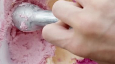 Dikey video. Dondurmanın üç farklı çeşidi ve renginde pembe olanın arasında kaşıkla bir top bej topluyorum..
